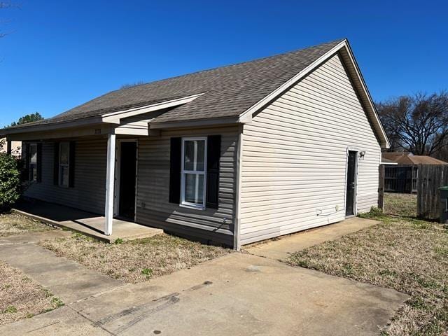 view of side of property featuring a shingled roof and fence