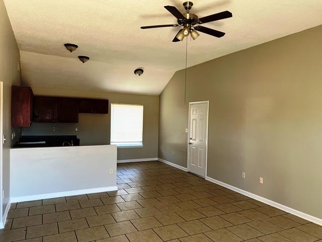 kitchen featuring baseboards, vaulted ceiling, and a ceiling fan