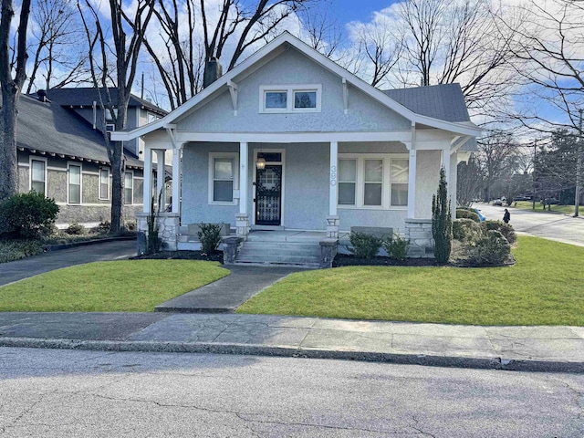 view of front facade featuring roof with shingles, stucco siding, a porch, driveway, and a front lawn