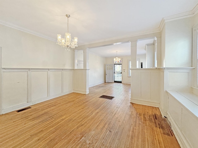 interior space featuring visible vents, an inviting chandelier, crown molding, light wood-type flooring, and a decorative wall