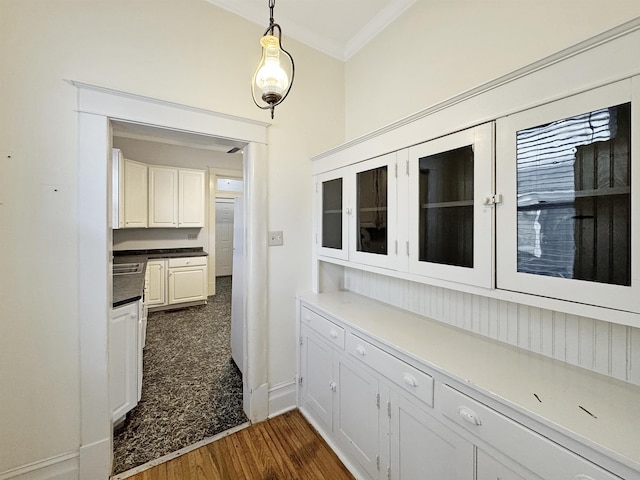 corridor featuring dark wood-style floors, ornamental molding, and baseboards