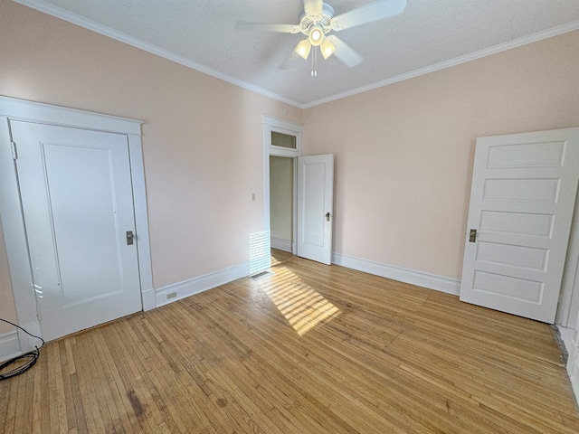 empty room with light wood finished floors, baseboards, ornamental molding, and a ceiling fan