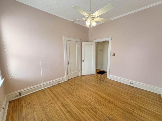 empty room with a textured ceiling, a ceiling fan, baseboards, light wood finished floors, and crown molding