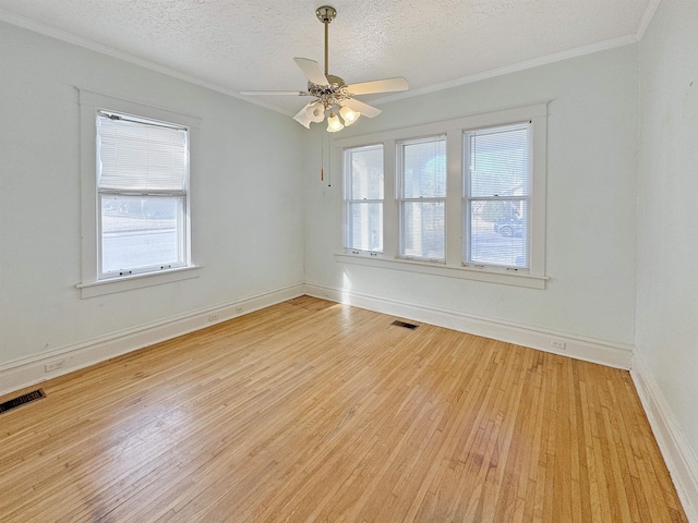 spare room with light wood-type flooring, baseboards, visible vents, and a textured ceiling