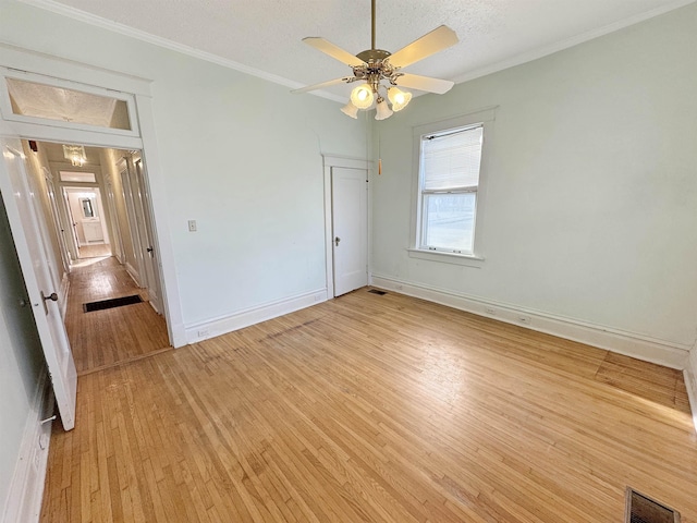 unfurnished bedroom featuring light wood-style floors, baseboards, visible vents, and crown molding