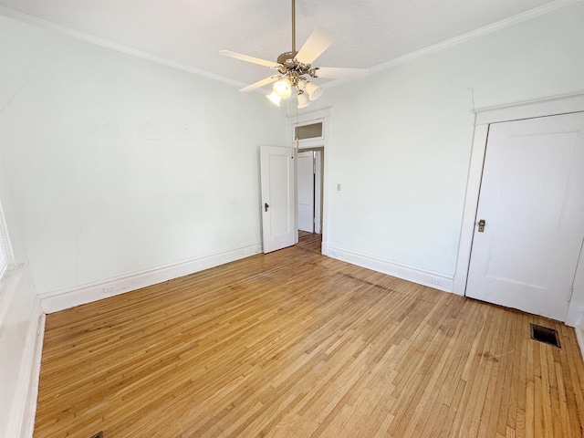 empty room featuring ornamental molding, baseboards, visible vents, and light wood finished floors