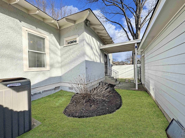 view of side of home with a yard, crawl space, cooling unit, and fence