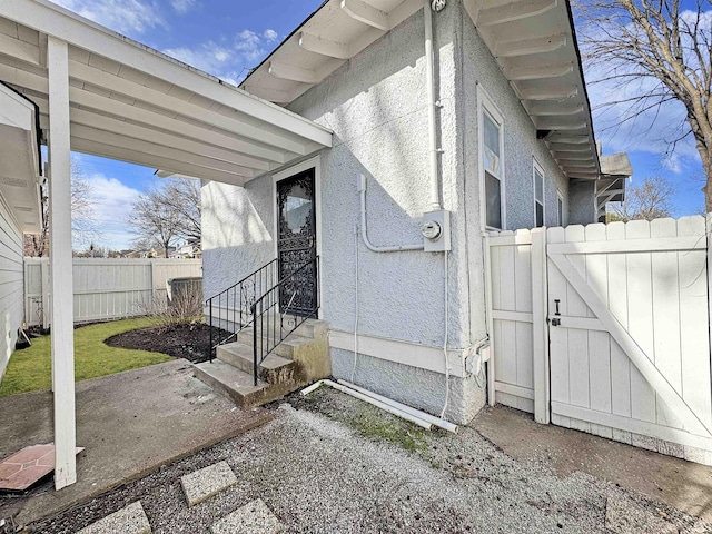 view of property exterior with entry steps, fence, and a gate