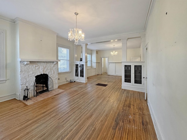 unfurnished living room with ornamental molding, light wood-type flooring, a fireplace, and an inviting chandelier