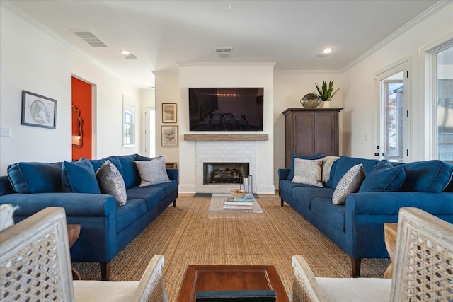 living room featuring a fireplace, visible vents, crown molding, and recessed lighting