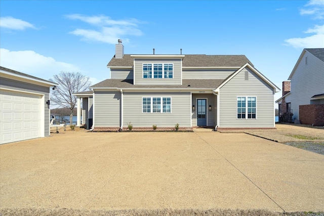 traditional-style home featuring a garage, driveway, a chimney, and roof with shingles