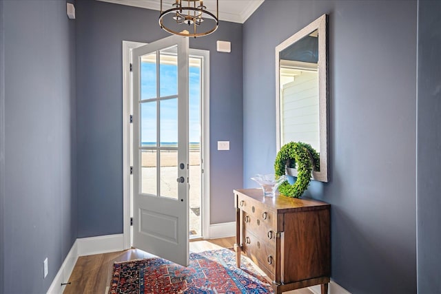 doorway featuring crown molding, wood finished floors, and baseboards