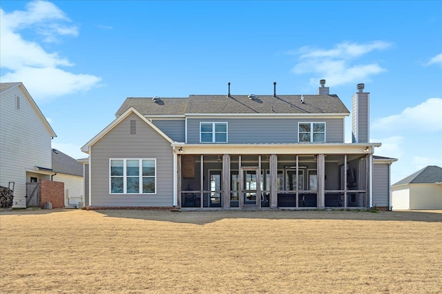 back of property featuring a sunroom, a lawn, and a chimney