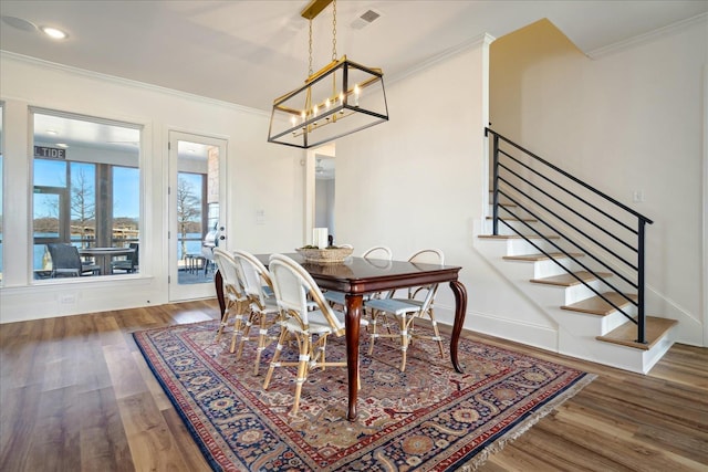 dining area with ornamental molding, stairway, wood finished floors, and visible vents