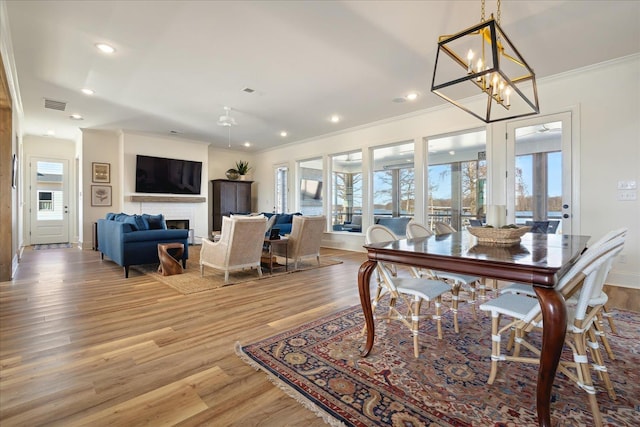 dining room with light wood finished floors, a fireplace, visible vents, and a wealth of natural light