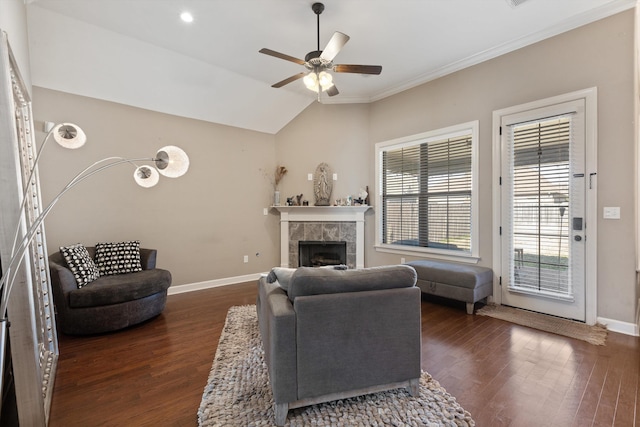 living area featuring dark wood-style floors, a tiled fireplace, lofted ceiling, and baseboards