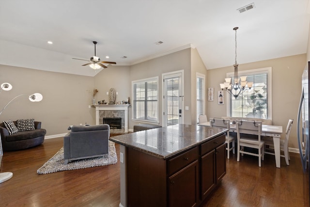 kitchen featuring baseboards, visible vents, dark wood finished floors, vaulted ceiling, and a fireplace