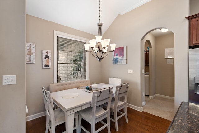 dining space with arched walkways, dark wood-style flooring, lofted ceiling, an inviting chandelier, and baseboards