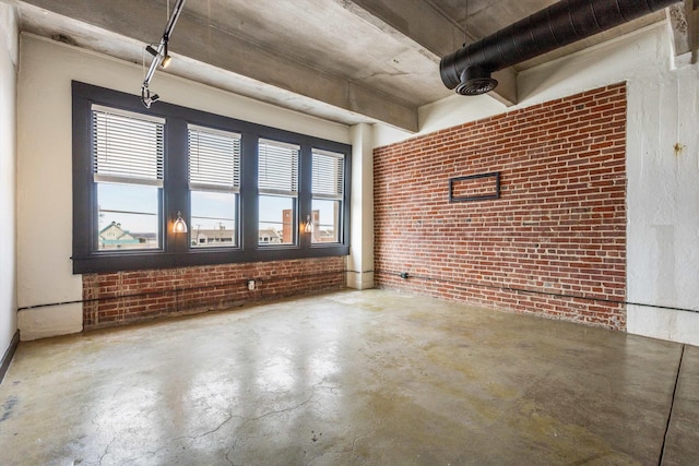 empty room featuring concrete flooring, a healthy amount of sunlight, and brick wall