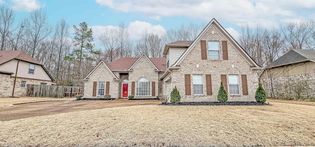 view of front of property with brick siding, fence, and a front lawn