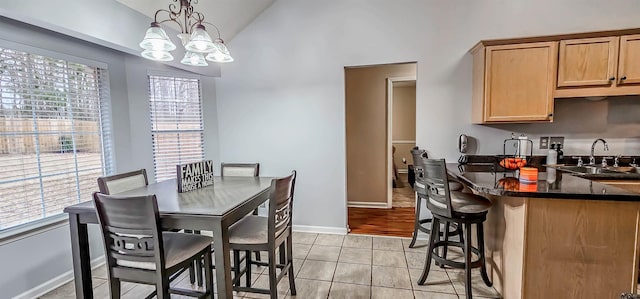 dining room with lofted ceiling, baseboards, an inviting chandelier, and light tile patterned floors