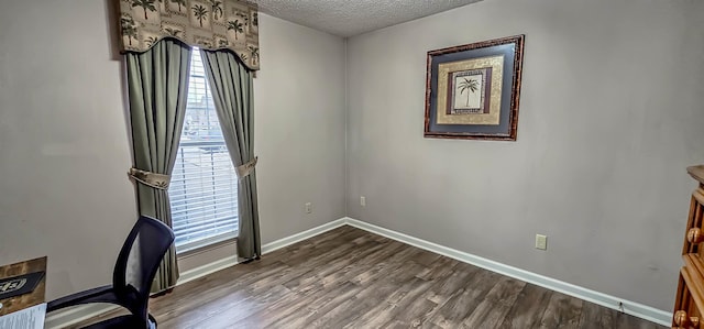 unfurnished office with baseboards, dark wood-style flooring, and a textured ceiling