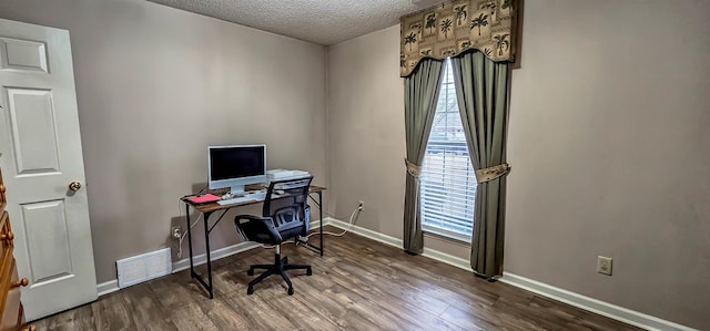 office space with baseboards, a textured ceiling, visible vents, and wood finished floors