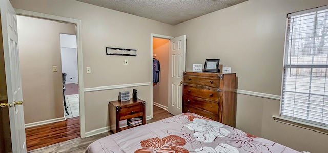 bedroom with a textured ceiling, wood finished floors, and baseboards