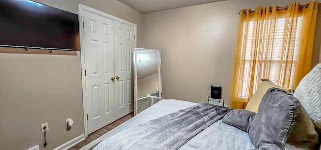 bedroom featuring a textured ceiling, a closet, and wood finished floors