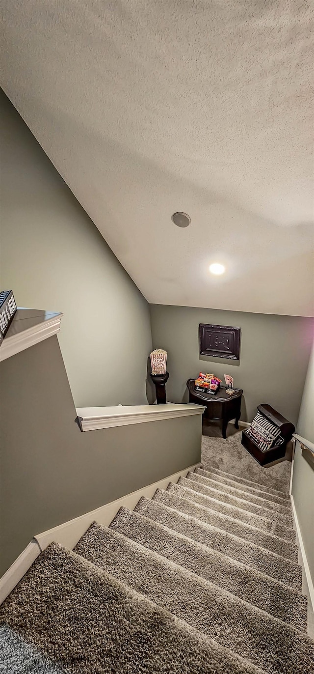 stairs featuring a textured ceiling, baseboards, vaulted ceiling, and carpet flooring