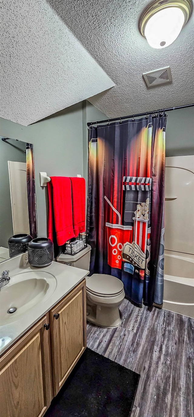 full bathroom featuring visible vents, a textured ceiling, toilet, and wood finished floors