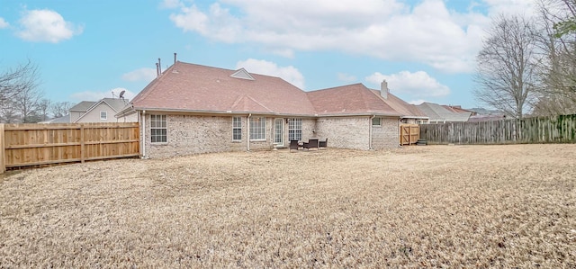 rear view of house with a fenced backyard and roof with shingles