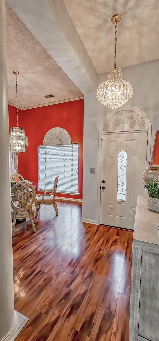 entryway featuring a chandelier, a textured ceiling, visible vents, baseboards, and hardwood / wood-style floors