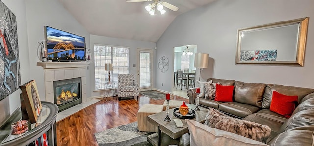 living area with vaulted ceiling, a tile fireplace, wood finished floors, and a ceiling fan