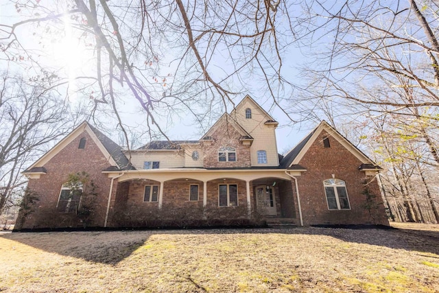 traditional-style house with a front lawn, a porch, and brick siding