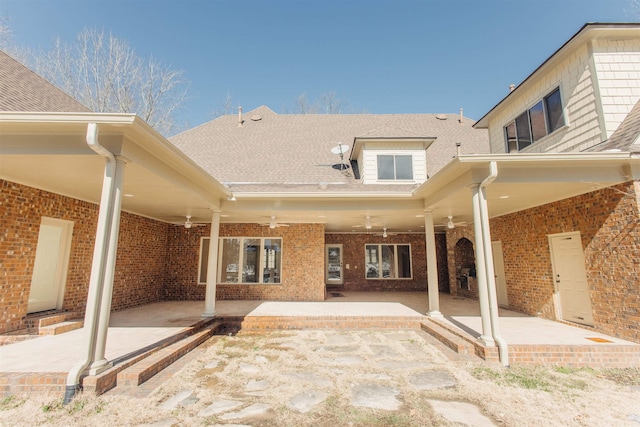 rear view of house featuring a patio area, ceiling fan, a shingled roof, and brick siding