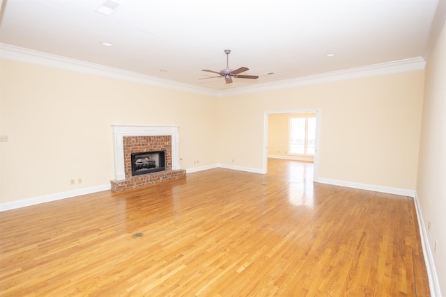 unfurnished living room with a brick fireplace, light wood-style floors, and crown molding