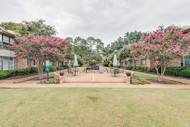 view of property's community featuring a lawn and a patio