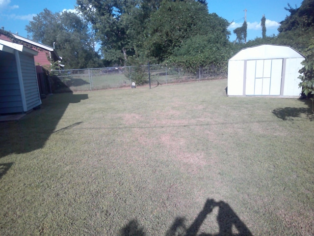 view of yard with a storage shed, fence, and an outbuilding