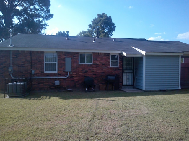 back of property featuring central AC, brick siding, and a lawn