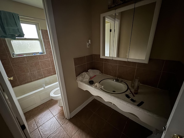 bathroom with baseboards, decorative backsplash, toilet, tile patterned flooring, and a sink