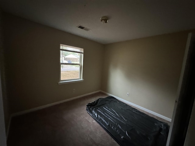 spare room featuring carpet, visible vents, and baseboards