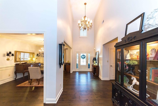 foyer featuring visible vents, wainscoting, dark wood-style floors, an inviting chandelier, and a decorative wall