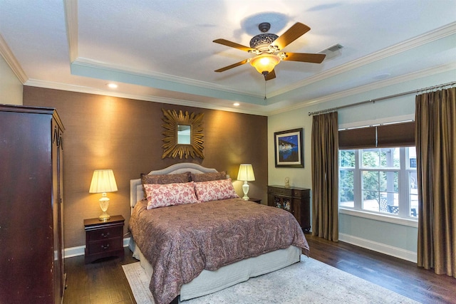 bedroom featuring a tray ceiling, visible vents, baseboards, and wood finished floors