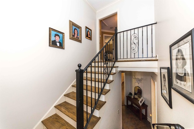 stairs featuring baseboards, a high ceiling, wood finished floors, and crown molding