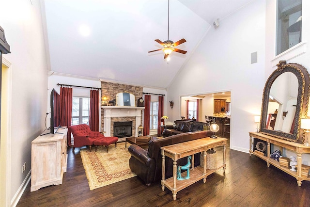 living room featuring dark wood finished floors, a stone fireplace, baseboards, and ceiling fan