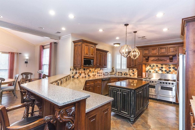 kitchen with light stone counters, a breakfast bar, appliances with stainless steel finishes, a sink, and a peninsula