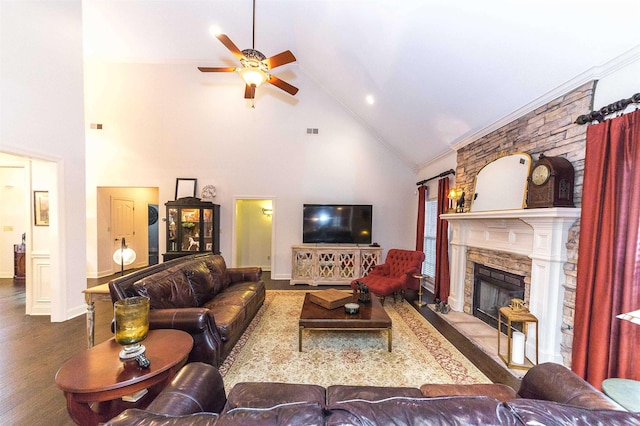 living room featuring visible vents, a ceiling fan, ornamental molding, wood finished floors, and a stone fireplace