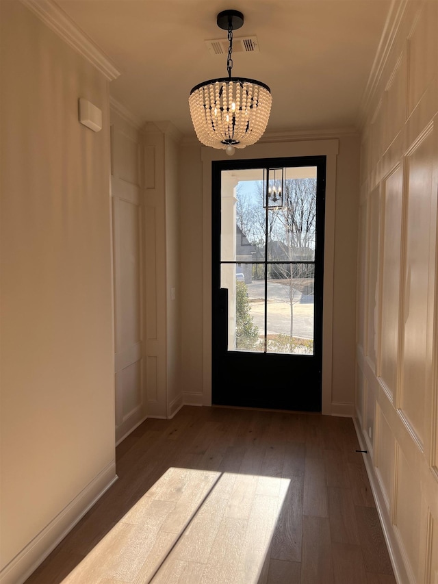 doorway with crown molding, visible vents, a chandelier, baseboards, and hardwood / wood-style flooring