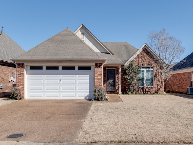 ranch-style home with a garage, central AC, brick siding, a shingled roof, and concrete driveway